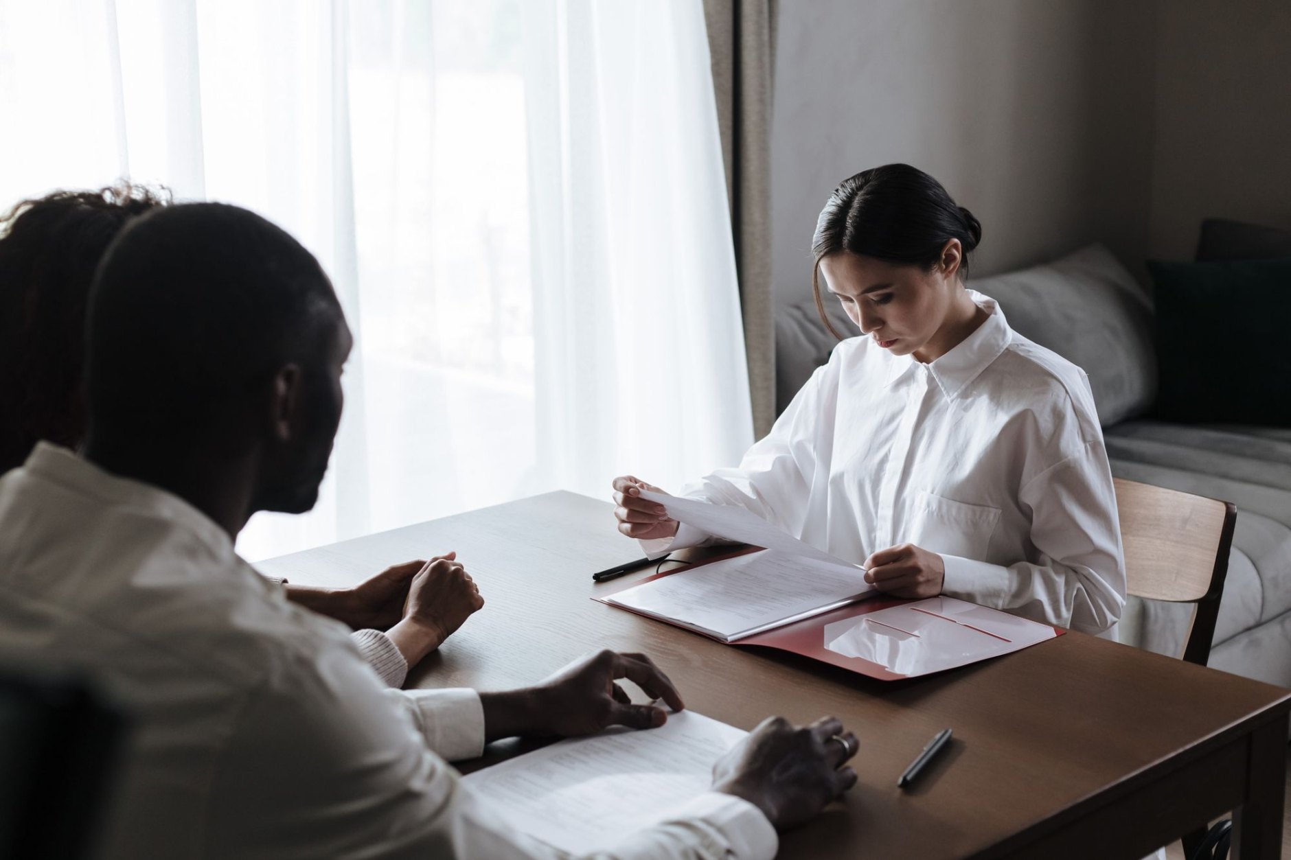 A couple reviewing financial documents with an adviser across a meeting table